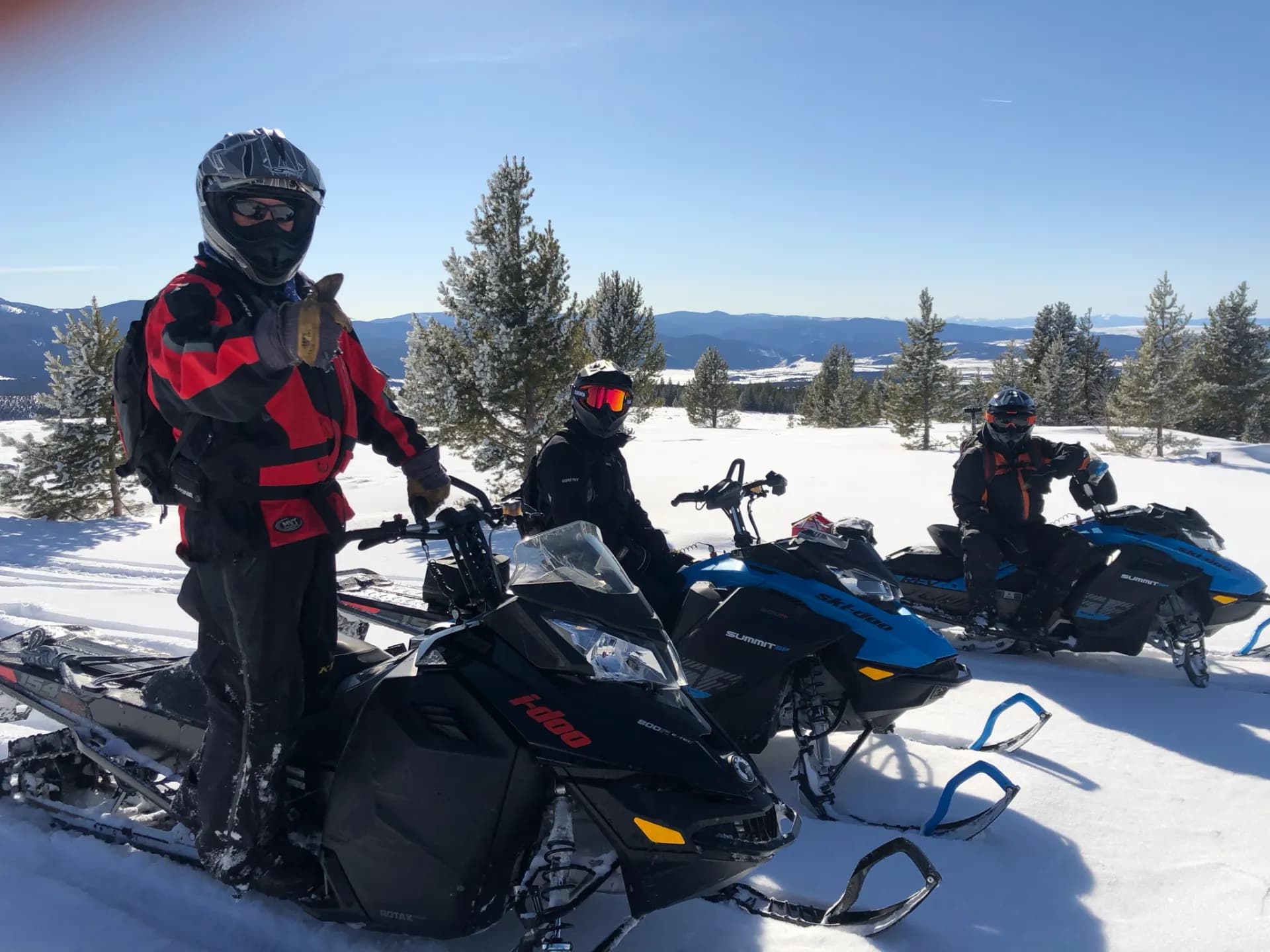 Group of riders on snowmobiles overlooking the Montana mountains
