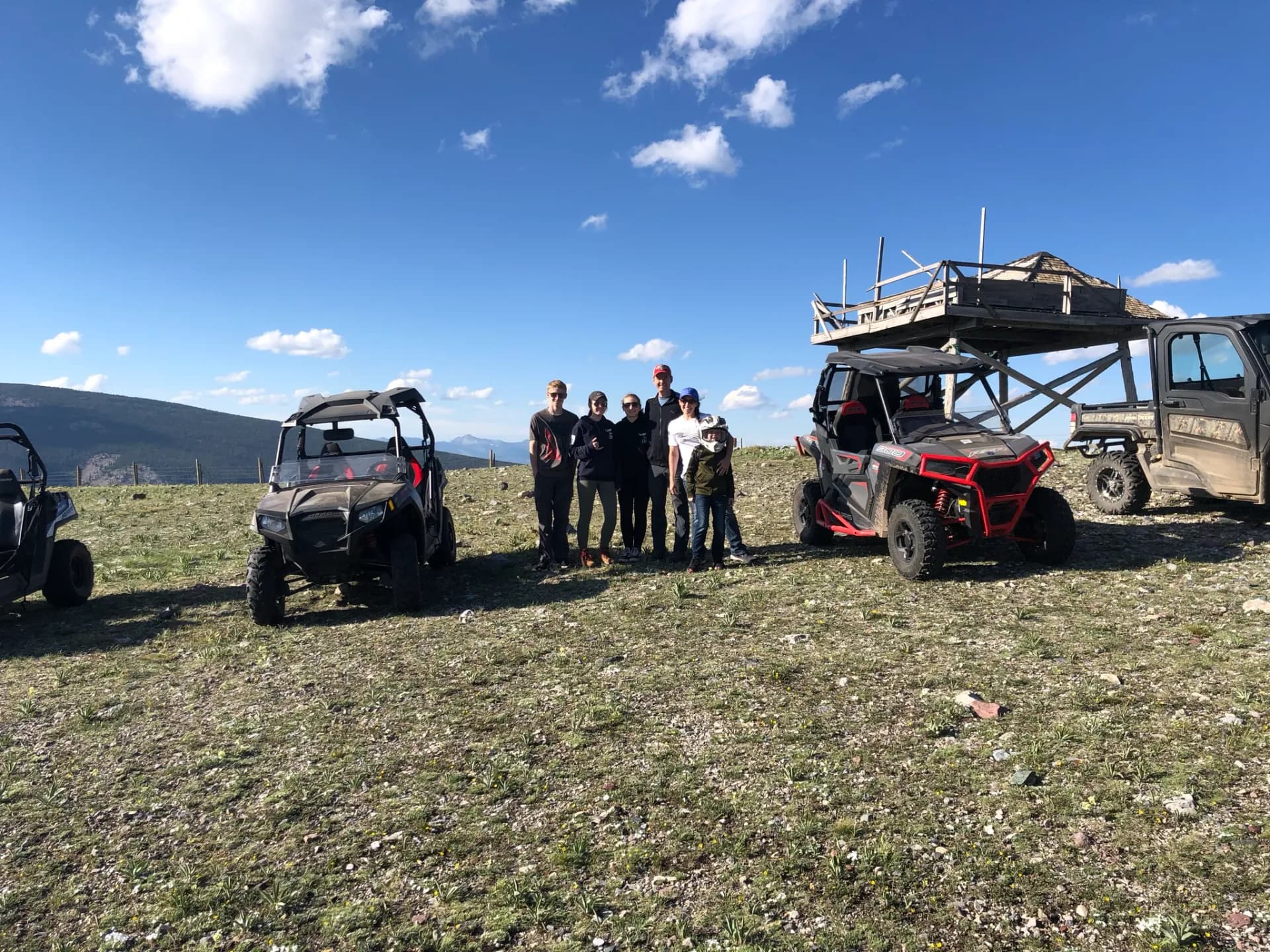 Riders with Polaris RZRs at a mountain overlook